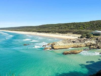 Coastal vista of turquoise water, rocky headland and long sandy beach on Minjerribah (North Stradbroke Island)