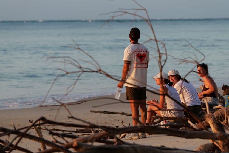 Tour group watching the sunset on a North Stradbroke Island beach amid driftwood