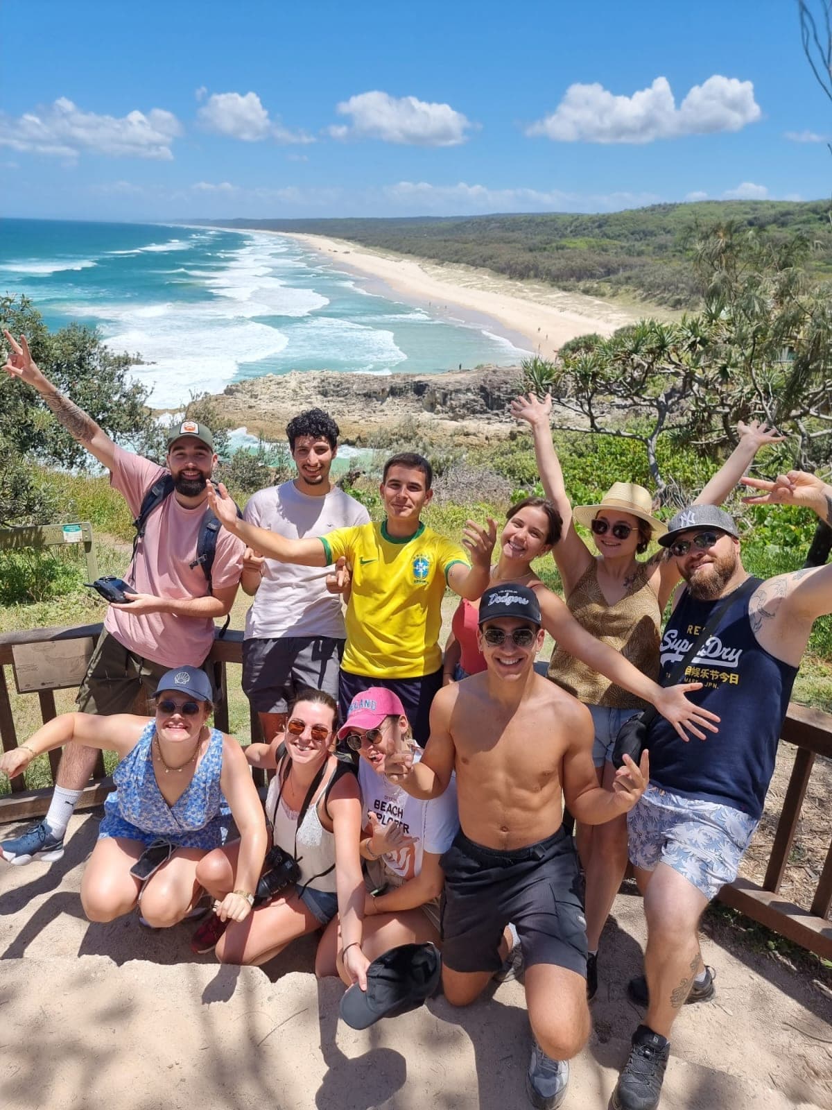 Tour group cheering at a North Stradbroke Island lookout with a long sandy beach behind