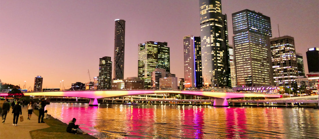 A stunning view of Brisbane city skyline during golden hour, with warm sunlight reflecting off the buildings and the Brisbane River below.